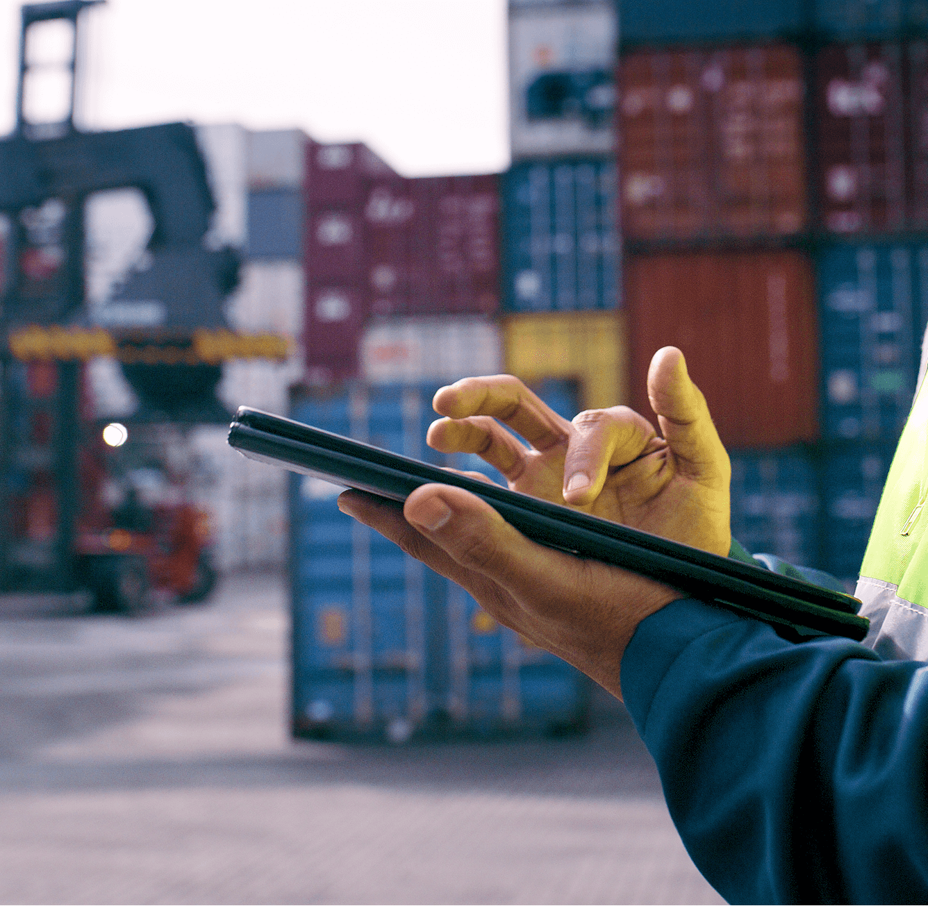 Person using tablet near shipping containers.